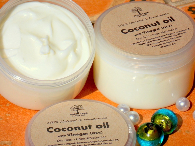 May include: Two glass jars of coconut oil with vinegar face moisturizer. The jars are labeled "100% Natural & Handmade Coconut oil with Vinegar (acv) Dry Skin - Face Moisturizer". The ingredients are listed on the label.
