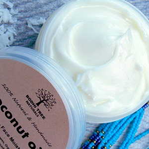 May include: A white jar with a brown label that reads "Coconut Oil" and "Dry Skin - Face Moisturizer". The label also includes the text "Bodhi Tree Naturals" and "100% Natural & Handmade". The jar is filled with a white cream.