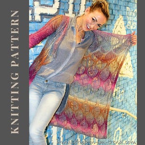 Könnte beinhalten: Eine lange, vorne offene Strickjacke mit einem Farbverlauf von tiefem Magenta und Violett zu Orange, Gelb und Blau. Das Kleidungsstück weist ein feines Lochstrickmuster auf und wird über einem grauen Hemd und einer Jeans getragen.