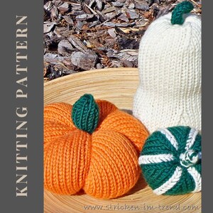 Könnte beinhalten: Gestrickte Kürbisse in Orange, Weiß und Grün, präsentiert auf einer Holzoberfläche. Der orangefarbene Kürbis hat einen grünen Stiel, während der weiße und grüne Kürbis weiße Akzente aufweisen. Das Bild enthält auch den Text "KNITTING PATTERN".