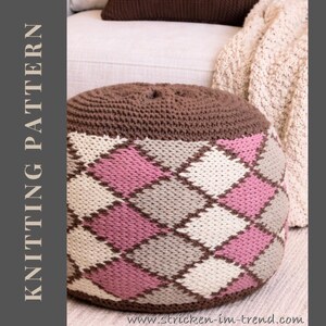 May include: A round knitted ottoman with a brown top and a patterned body. The body features a diamond pattern in pink, white, and gray. The text "KNITTING PATTERN" is visible on the left side.