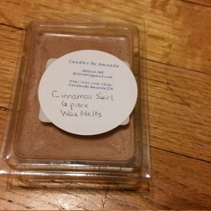 Peut inclure: Un r&eacute;cipient en plastique transparent contenant une fonte de cire brune. L'&eacute;tiquette indique "Candles By Amanda", "Milford, MI", "CandlesByAmanda.com", "http://etsy.com/shop/CandlesByAmanda229", "Cinnamon Swirl", "6 piece", "Wax Melts".