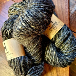 Könnte beinhalten: Eine Knäuel Alpaca Blend Garn in einem dunkelgrauen und weißen Farbton. Das Etikett lautet "Alpaca Blend 90% Alpaca 20% Seide Faser Reece von Nico 159 Yards 7,7 oz 1 Lopi".