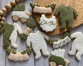Puede incluir: Un conjunto de diez galletas de azúcar decoradas con un tema de bebé. Las galletas están decoradas con glaseado verde y blanco y presentan diseños como un cochecito, un sonajero y las palabras "Oh Boy" y "Baby".