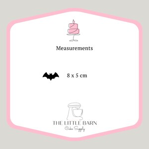 May include: Pink and white cake topper shaped like a bat, measuring 8 by 5 centimeters. The topper is made by The Little Barn Cake Supply.