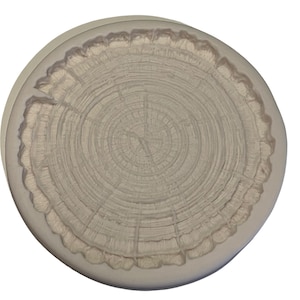 May include: A round silicone mould with a detailed tree ring design. The mould is light brown and has a smooth surface.