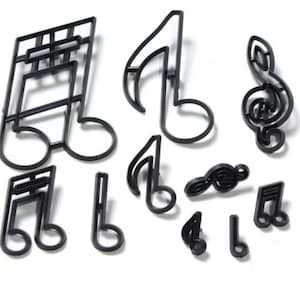 May include: A set of 10 black plastic cookie cutters shaped like different musical notes. The cutters include a treble clef, a bass clef, a whole note, a half note, a quarter note, an eighth note, and a sixteenth note.