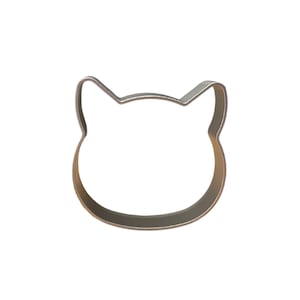 May include: A silver metal cookie cutter shaped like a cat's face.