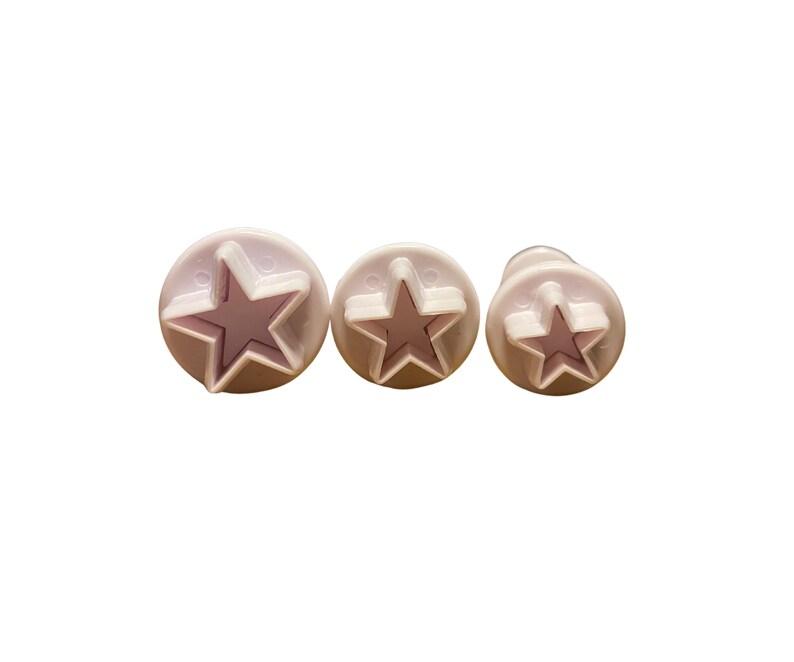 May include: Three white plastic star-shaped cookie cutters of different sizes.