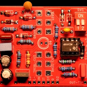 Peut inclure: Une carte de circuit imprim&eacute; rouge marqu&eacute;e SlimTim v1.0 comprenant divers composants &eacute;lectroniques, notamment des r&eacute;sistances bleues, jaunes et brunes, une puce de circuit int&eacute;gr&eacute; noire marqu&eacute;e MC1458P, un interrupteur blanc et des condensateurs.