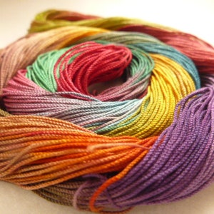 May include: A close-up of a bundle of colourful embroidery floss, including shades of purple, orange, yellow, green, and red.