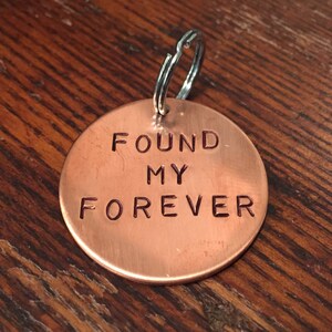 May include: A copper keychain with the words "FOUND MY FOREVER" engraved on it.