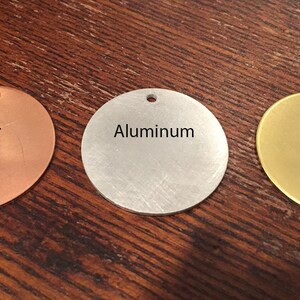 May include: Three round metal discs, each with a different finish: copper, aluminum, and brass. The discs have a hole in the center.