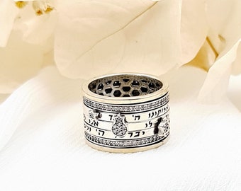 May include: A silver ring with a textured band and Hebrew writing. The ring is set with small clear stones.