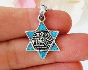 May include: A silver pendant in the shape of a six-pointed star with blue opal stones. The star has a design of a building inside with Hebrew writing.