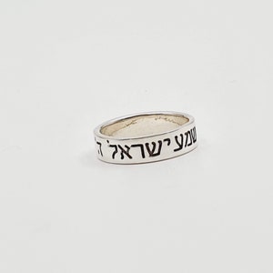 Puede incluir: Un anillo de plata con las palabras hebreas "עשה לך" grabadas en la banda.