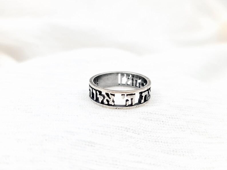 May include: A silver ring with Hebrew lettering engraved around the band.