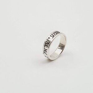 Puede incluir: Un anillo de plata con texto hebreo grabado alrededor de la banda.