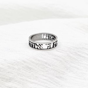 May include: A silver ring with Hebrew lettering engraved around the band.