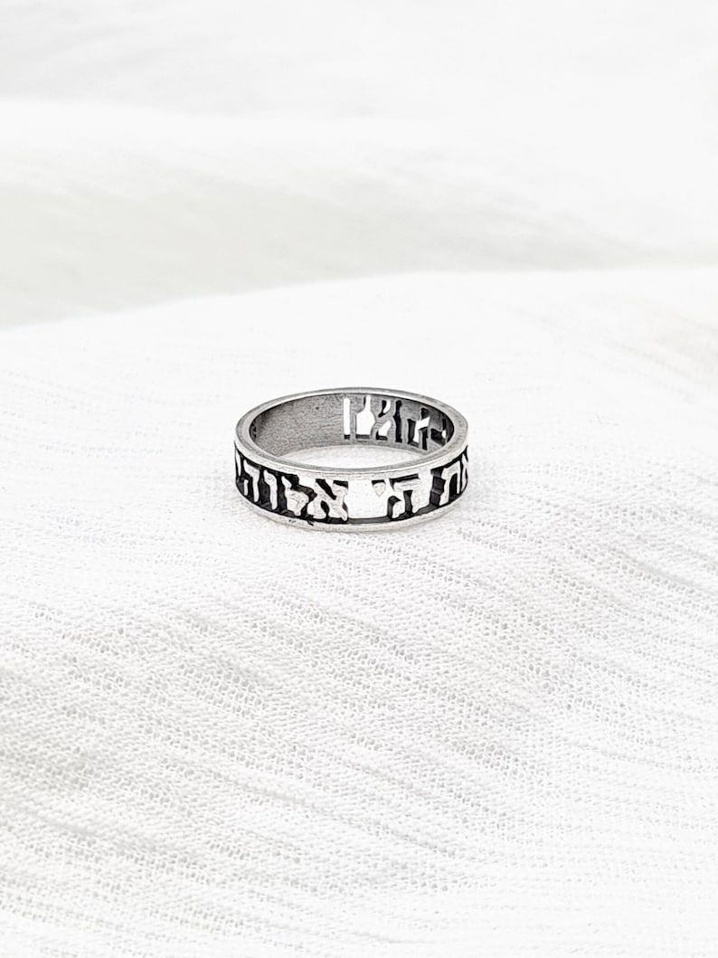 May include: A silver ring with Hebrew lettering engraved around the band.
