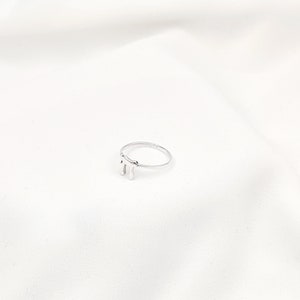 May include: A silver ring with a drip design. The ring is simple and modern.
