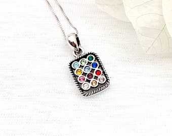 May include: A silver necklace with a rectangular pendant featuring a colorful mosaic of small round gemstones. The pendant is surrounded by a silver rope border.