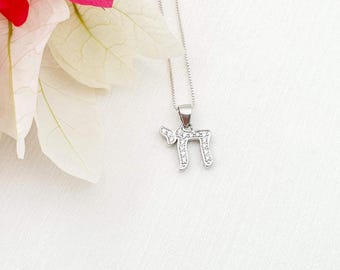 May include: A silver chain necklace with a pendant shaped like the Hebrew letter 'Chai' (life) with clear cubic zirconia stones.