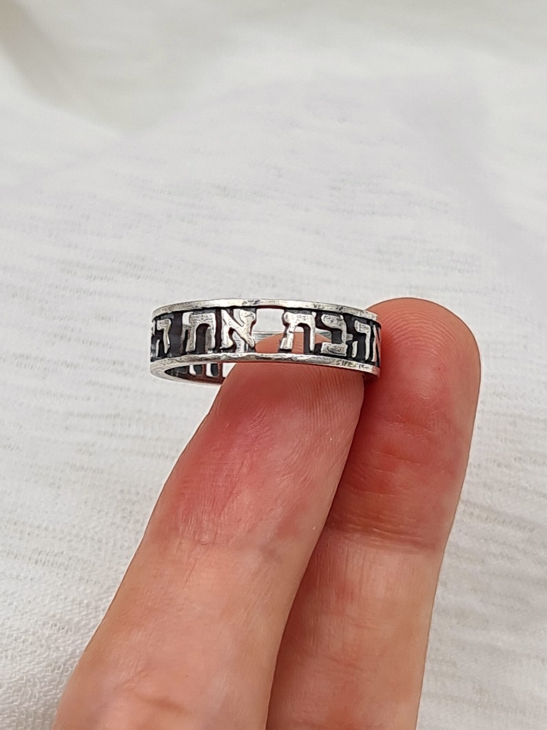 May include: A silver ring with Hebrew lettering around the band.