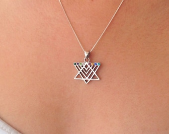 May include: A silver necklace featuring a Star of David pendant. The pendant is adorned with colorful gemstones. The necklace is displayed against a skin-toned background, highlighting the jewelry's design and details.