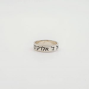 Puede incluir: Un anillo de plata con las palabras hebreas "אהיה אלקיך" grabadas en la banda.