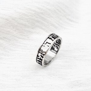 May include: A silver ring with Hebrew lettering engraved around the band.