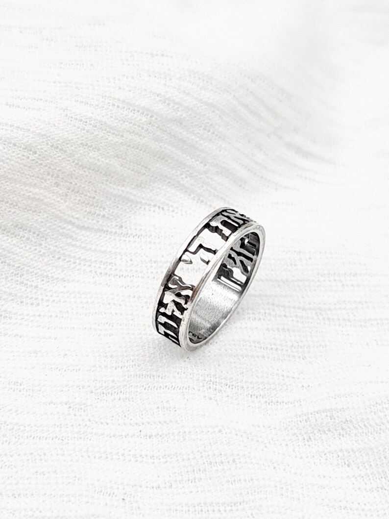 May include: A silver ring with Hebrew lettering engraved around the band.