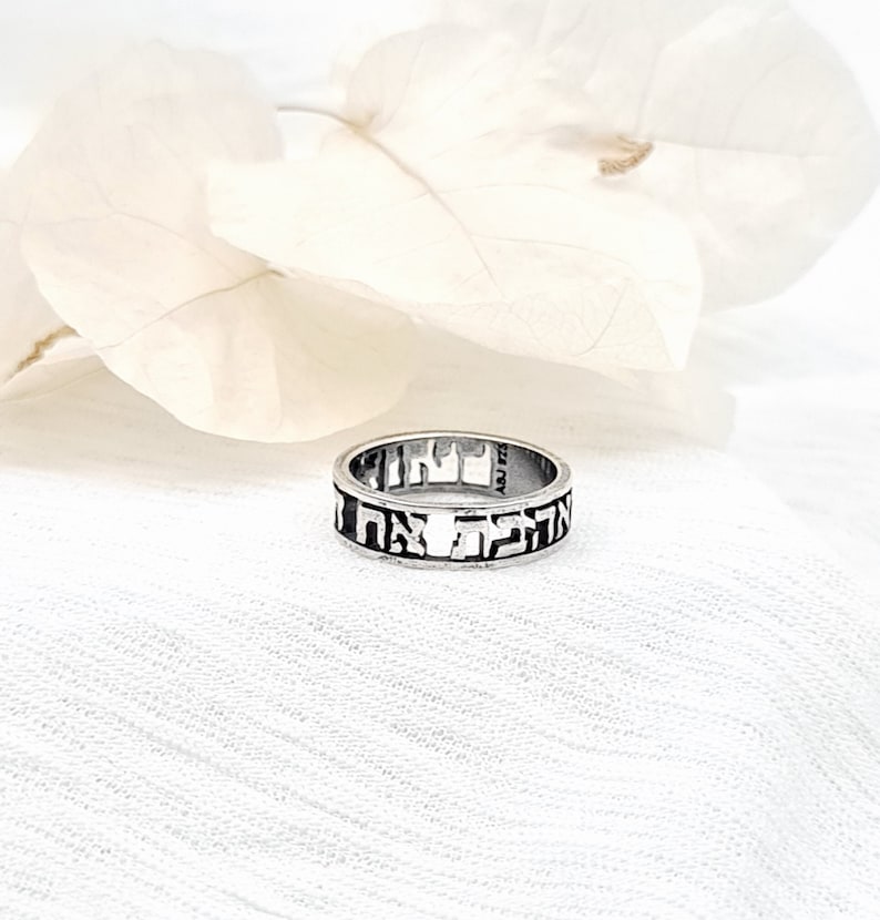 May include: A silver ring with Hebrew lettering engraved around the band.