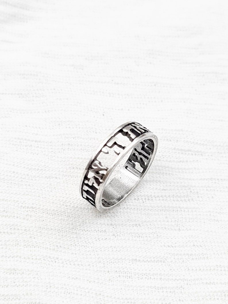 May include: A silver ring with Hebrew lettering engraved around the band.