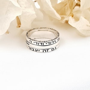 May include: A silver ring with Hebrew text inscribed on it. The ring is made of two bands, one slightly larger than the other. The text on the ring reads "Am Yisrael Chai" which means "The people of Israel live".