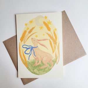 Tarjeta de felicitación de cumpleaños y aniversario con la liebre lunar observando la luna y el solsticio
