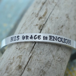 May include: A silver bracelet with the words "His Grace is Enough" engraved on it.