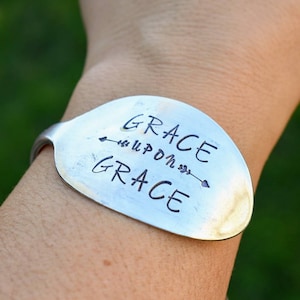 May include: A silver spoon bracelet with the words "GRACE upon GRACE" engraved on it.