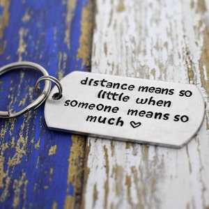 May include: Silver keychain with a heart and the text "Distance means so little when someone means so much".