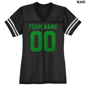 Puede incluir: Camiseta de f&uacute;tbol negra con rayas blancas en las mangas. La camiseta tiene un nombre de equipo y un n&uacute;mero "00" en purpurina verde.