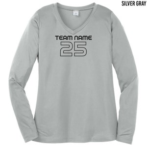 以下が含まれることがあります： Vネックのシルバーグレーのロングスリーブシャツ。シャツには「TEAM NAME」という黒い文字と、太字のブロック体で「25」という数字が書かれています。