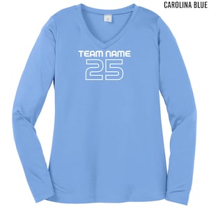 以下が含まれることがあります： 白のVネックと「TEAM NAME 25」の文字が前面にプリントされた、カロライナブルーの長袖シャツです。