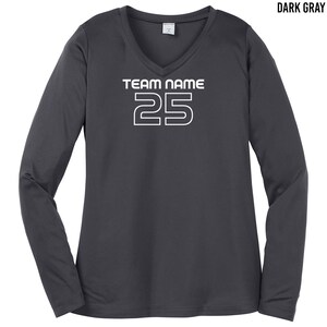以下が含まれることがあります： Vネックのダークグレーのロングスリーブシャツ。シャツには「TEAM NAME」という白い文字と、太字で縁取りされたフォントで「25」という数字が書かれています。