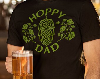 Könnte beinhalten: Ein schwarzes T-Shirt mit einer grünen Grafik eines Hopfenzapfens und dem Text "Hoppy Dad".