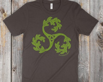 May include: A dark gray t-shirt with a green leafy triquetra design and the text "RambleTree" below it. The text "RambleTree (Quercus alba) Original artwork ©2016 Reagh Greenleaf Jr." is printed at the bottom of the shirt.