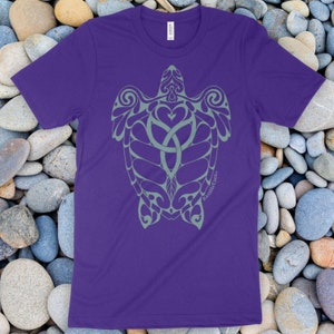 May include: A purple short-sleeved t-shirt featuring a light green graphic of a sea turtle with intricate, swirling, tribal-inspired patterns on its shell and flippers. The text "RambleTree" is printed in small letters near the turtle's right flipper.