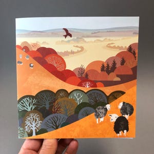 May include: A colorful illustration of a landscape with a winding river, trees in shades of red, orange, and green, and a flock of sheep in the foreground. The sky is a light blue with a single bird flying overhead.