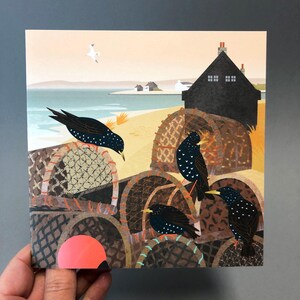 May include: A colorful illustration of a seaside scene with four black birds perched on top of stacked fishing baskets. The birds have white spots and yellow beaks. The background shows a small village with a dark blue house and a light blue sea.