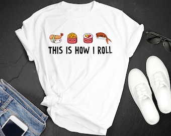 May include: White t-shirt featuring the text "THIS IS HOW I ROLL" and sushi illustrations. The image includes blue jeans, white trainers, and sunglasses, all arranged on a black surface.