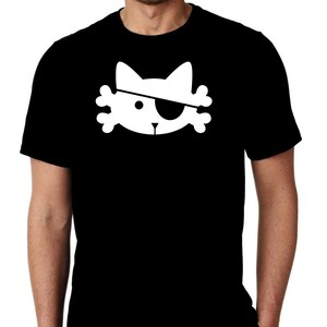 以下が含まれることがあります： 黒いTシャツ。白いグラフィックは、眼帯と骨付きの猫の顔です。猫のデザインは海賊をテーマにしています。シャツは柔らかい素材で作られています。